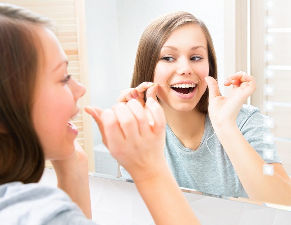woman flossing in the mirror