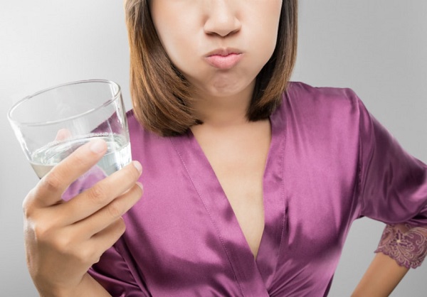 woman gargling using a glass of water