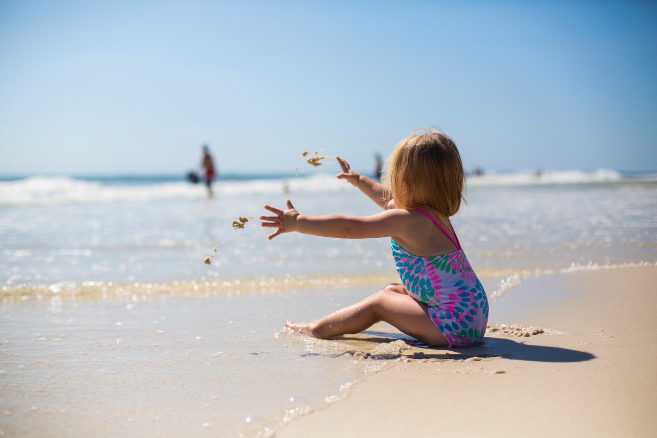 adorable baby girl playing on the sand beach under the sun