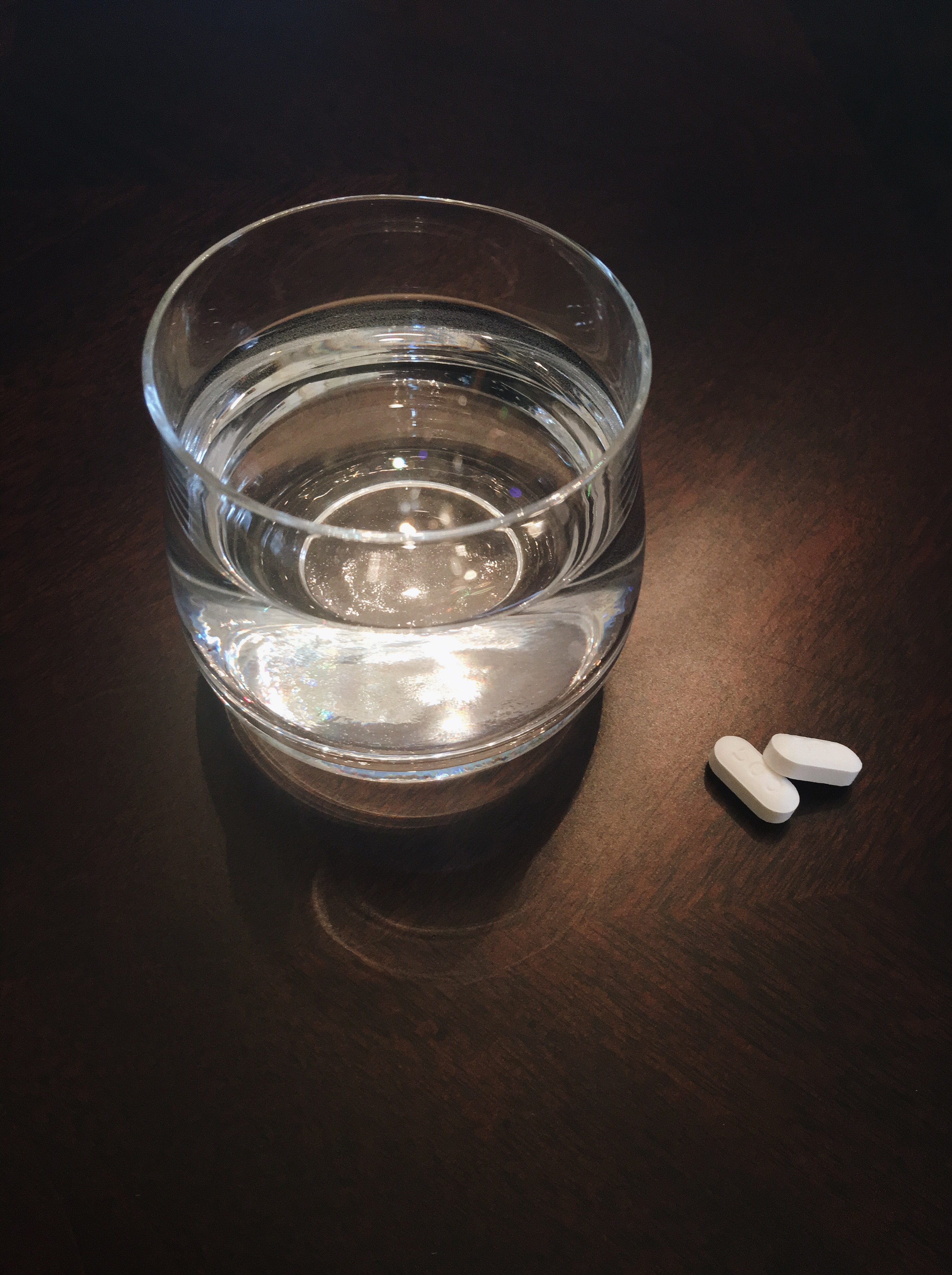 a glass of water and two vitamin tablets